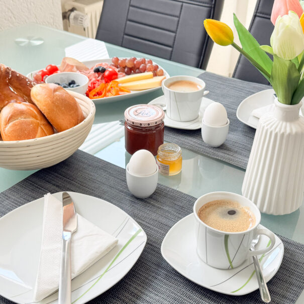 Gedeckter Frühstückstisch mit Tulpen und Brotkorb