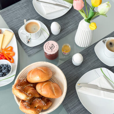 Frühstückstisch mit Brötchen, Kaffee und frischen Zutaten