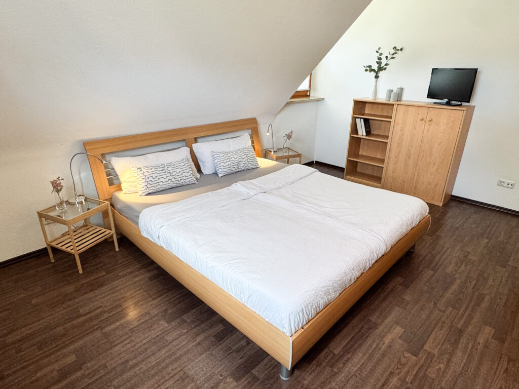 Doppelbett mit Nachttischen und Fernseher