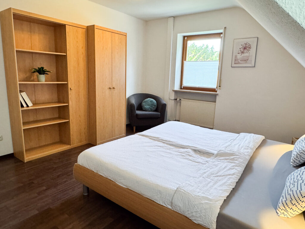 Schlafzimmer mit Regal und Sessel